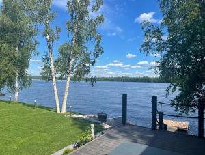 un banco sentado en un muelle junto al agua en Villa by the river with beach sauna and jacuzzi, en Rovaniemi