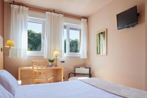 a bedroom with a bed and a desk and a television at Iraipe Santuario de Arantzazu Hotel in Oñate