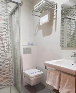 Baño blanco con aseo y lavamanos en Hostal La Colonia, en Marbella