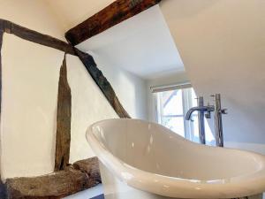 a bathroom with a large white bath tub in a room at Mortimer Cottage in Wootton Rivers