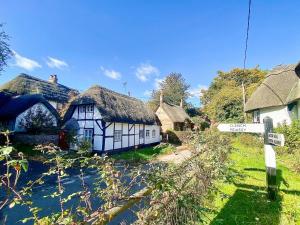 - un village avec des cottages au toit de chaume et un panneau indiquant la rue dans l'établissement Mortimer Cottage, à Wootton Rivers