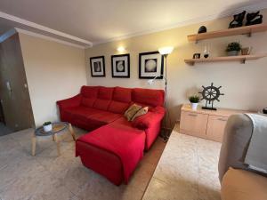 a living room with a red couch and a table at Las Nasas, Acogedor apartamento cerca de la playa in Arinaga