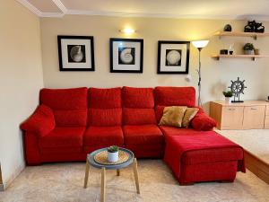 a red couch in a living room with a table at Las Nasas, Acogedor apartamento cerca de la playa in Arinaga