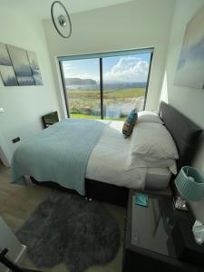 Schlafzimmer mit einem Bett und einem großen Fenster in der Unterkunft Flora's Cliff View in Kilmuir