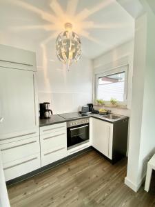 uma cozinha com armários brancos e um lustre em Willinger Perle em Willingen