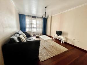 a living room with a black couch and a table at Agradable apartamento céntrico en Cangas in Cangas de Morrazo