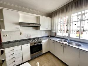 a white kitchen with a sink and a stove at Agradable apartamento céntrico en Cangas in Cangas de Morrazo