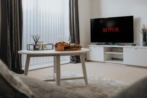 ein Wohnzimmer mit einem Tisch und einem TV in der Unterkunft Lovely Modern 2 Bed City Centre Apartment with FREE parking - Double or Twin Beds Available in Wolverhampton