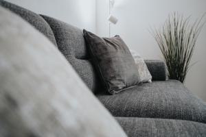 a gray couch with a pillow in a living room at Lovely Modern 2 Bed City Centre Apartment with FREE parking - Double or Twin Beds Available in Wolverhampton