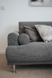 um sofá cinzento com uma almofada num quarto em Lovely Modern 2 Bed City Centre Apartment with FREE parking - Double or Twin Beds Available em Wolverhampton