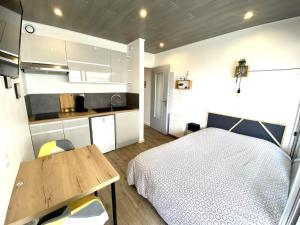ein Schlafzimmer mit einem Bett und einem Tisch sowie eine Küche in der Unterkunft Le moulin vieux in Pontarlier