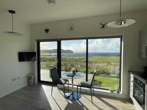 eine Küche mit einem Tisch und Stühlen sowie einem großen Fenster in der Unterkunft Flora's Cliff View in Kilmuir