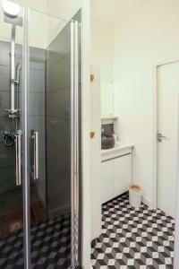 La salle de bains est pourvue d'une douche et d'un sol en damier noir et blanc. dans l'établissement Confortable T2 à Saint Aubin, à Toulouse