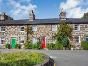 a stone house with a red door and green windows at Bro Dawel in Dolgellau