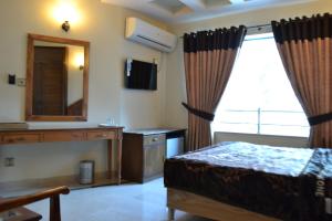 a bedroom with a bed and a mirror and a window at Hotel de Palazzo in Islamabad