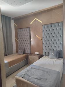 a bedroom with two beds and a headboard at Ap 2ch city centre parking en face Hilton a cote du plage in Tangier