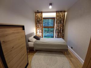 um pequeno quarto com uma cama e uma janela em Dom Winiarza em Krosno