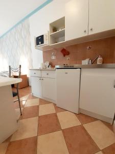 a kitchen with white cabinets and a tile floor at Petra Apartmanház in Kehidakustány