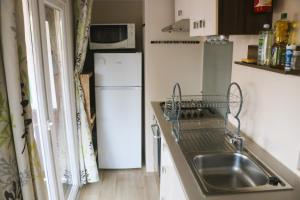 a small kitchen with a sink and a refrigerator at Mobil-Home 3 chambres à "Les Mathes" in Les Mathes