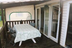 un porche cubierto con mesa y sillas en Mobil-Home 3 chambres à "Les Mathes" en Les Mathes