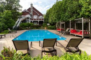 een zwembad met stoelen en een huis bij Le Baluchon Éco-villégiature in Saint-Paulin