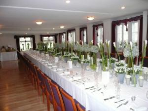 a long table with chairs and vases with flowers at Gasthof Löwen in Bubikon