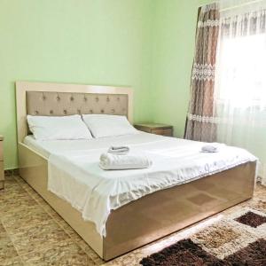 a bedroom with a bed with white sheets and a window at Relax Hostel in Tirana