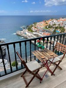 einen Holztisch und einen Stuhl auf einem Balkon mit Meerblick in der Unterkunft Amazing sea views from cozy studio. in Puerto de Santiago