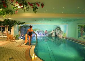 a woman is standing next to a swimming pool at Boutiquethotel Grandau in Sankt Gallenkirch