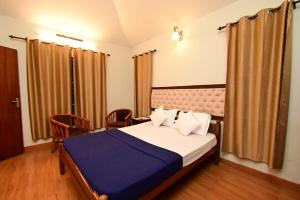 a bedroom with a bed and chairs in a room at Green Valley Holiday Home in Meppādi +21 photos