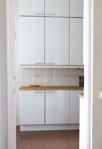 a white kitchen with white cabinets and a counter at 2ndhomes City Center 2BR Apartment with Balcony and Sauna by Kaisaniemi Park in Helsinki