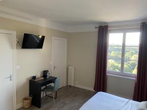 ein Hotelzimmer mit einem Schreibtisch, einem Bett und einem Fenster in der Unterkunft Hotel De La Poste in Mortain