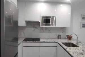 a kitchen with white cabinets and a stainless steel microwave at Piso en el Centro de La Cala in Mijas Costa