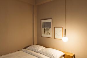 a bedroom with a bed with a lamp and pictures at Maplewood Hotel Chiangmai in Chiang Mai