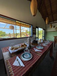 a table with food on it in a room with windows at Pousada Flor do Rio in Caraíva