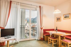een woonkamer met een groot raam en een tafel met een televisie bij Aquila Dolomites Residence in Ortisei