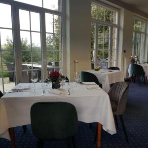 comedor con 2 mesas, sillas y ventanas en Hotel De La Poste, en Mortain