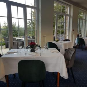 a dining room with two tables and chairs and windows at Hotel De La Poste in Mortain