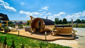 a small wooden cabin with a wooden deck at Apartamenty Grapa Resort 2xSauny 2xSale zabaw Balia Kulkolandia in Białka Tatrzańska