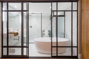 uma casa de banho com uma banheira branca e paredes de vidro em Victory Business Hotel em Juiz de Fora