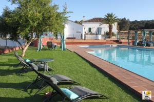 a villa with a swimming pool and a motorcycle parked in the grass at Cortijo Huerta Galindo in Alanís