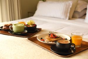 - un plateau de petit-déjeuner avec du café et des aliments pour le petit-déjeuner sur un lit dans l'établissement Maison Italia 1029, à Santiago