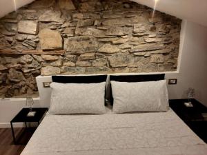 a bedroom with a stone wall and a bed with pillows at Luxury Room La Terrazza sul Lago di Como in Blevio