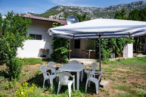 una mesa y sillas bajo una sombrilla en un patio en Vikendica Nina, en Čanj