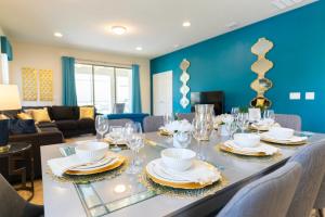 uma sala de jantar com uma mesa com pratos e copos em Blue Stylish Charming Villa with Pool near Disney em Kissimmee