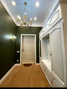 a hallway with green walls and a chandelier at Квартира студия in Almaty