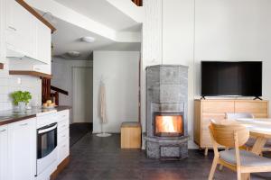 a kitchen with a fireplace with a table and a television at Alppitähti, Huoneisto Hilla in Levi