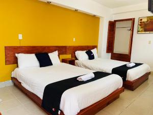 2 camas en una habitación de hotel con paredes amarillas en Hotel Dulce Luna, en San Cristóbal de Las Casas