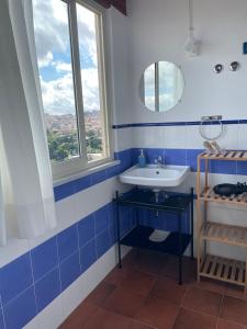 baño azul y blanco con lavabo y ventana en La Casa della Nonna en Cammarata
