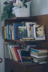 uma estante cheia de livros e um cesto de flores em Una Civetta sul Lago em Alleghe
